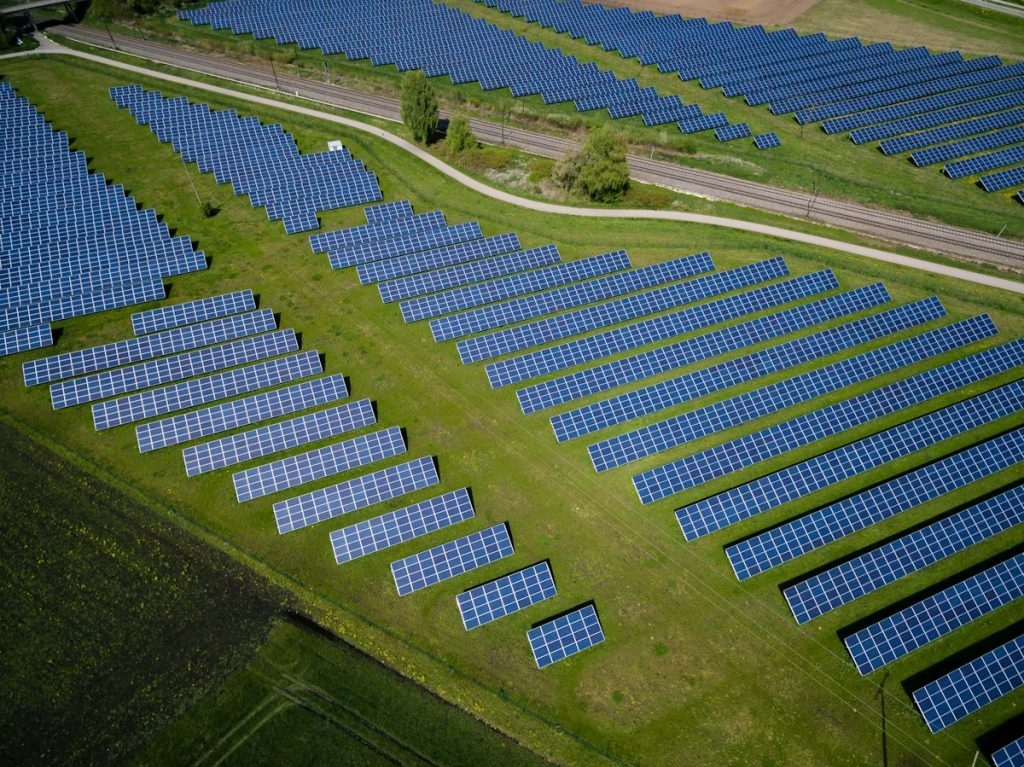 Aerial view of solar panel rows across a grass field