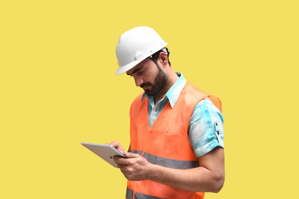 Engineer in a hard hat reviewing a site survey on a tablet
