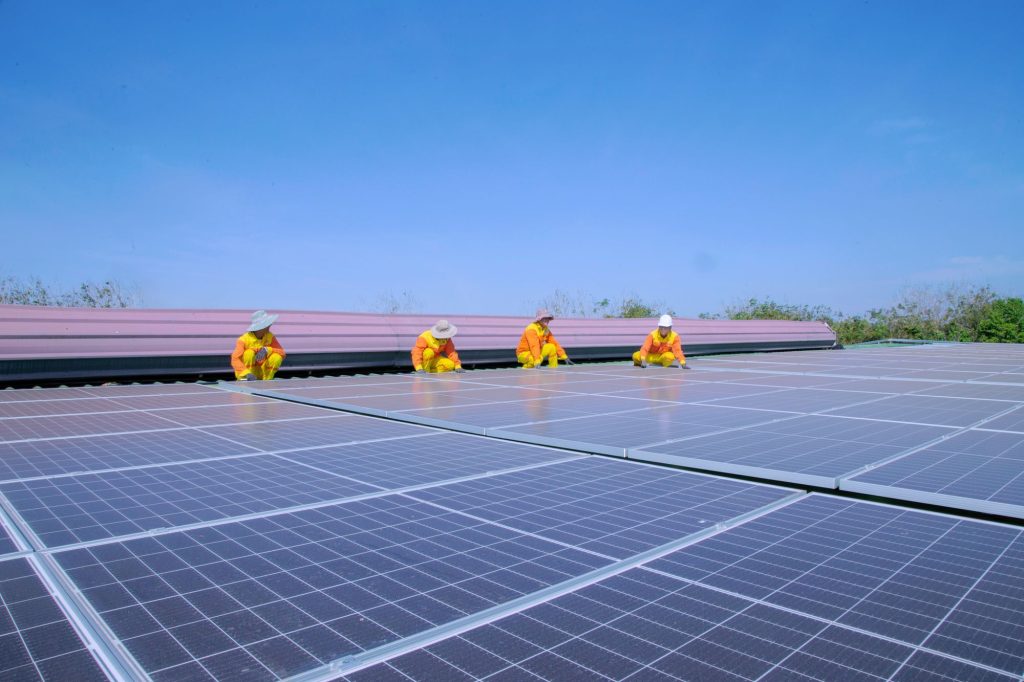 Solar installation team fitting panels on a rooftop under a clear sky