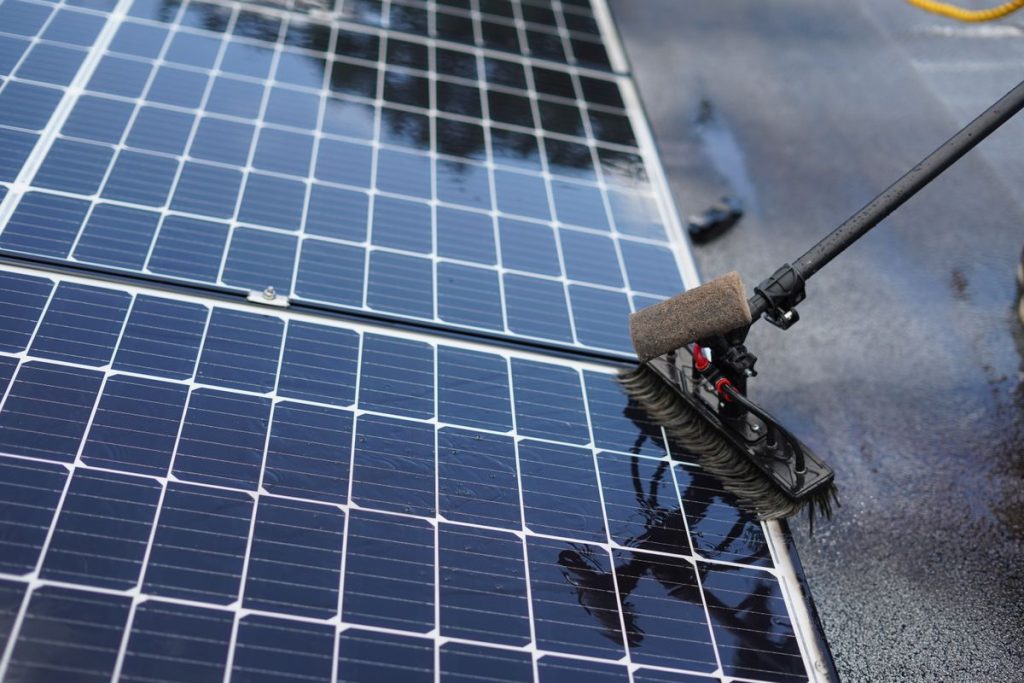 Close-up of a solar panel being cleaned with a brush tool