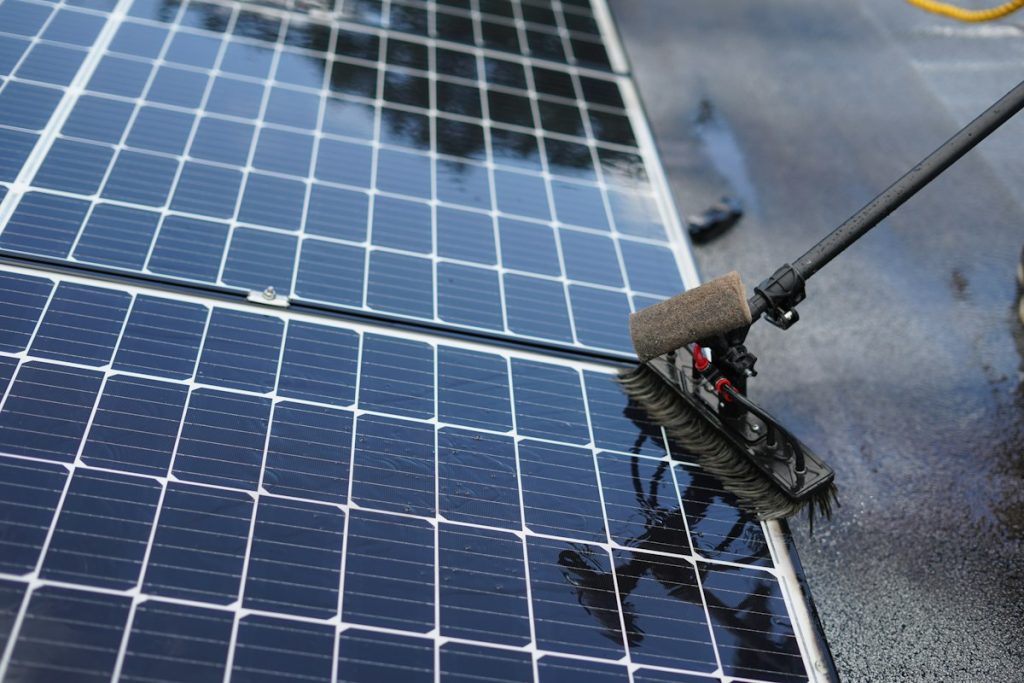 Cleaning solar panels with a long-handled soft brush
